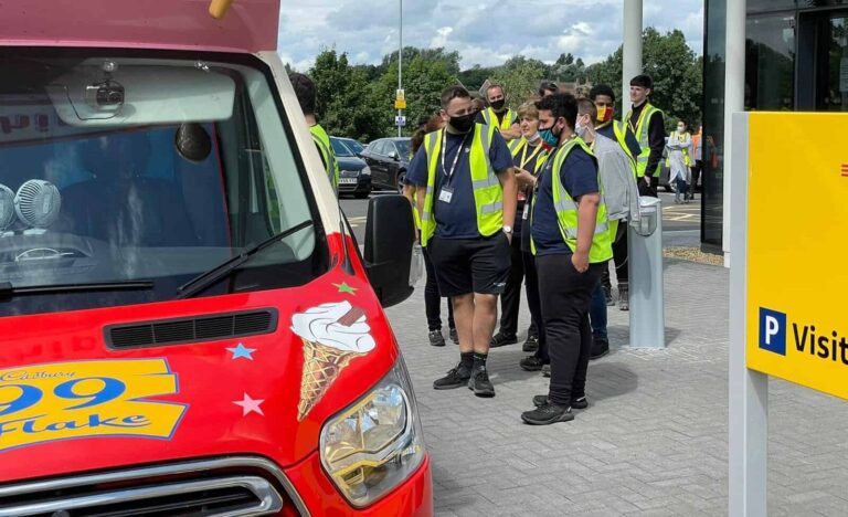 people in safety jackets standing near a van